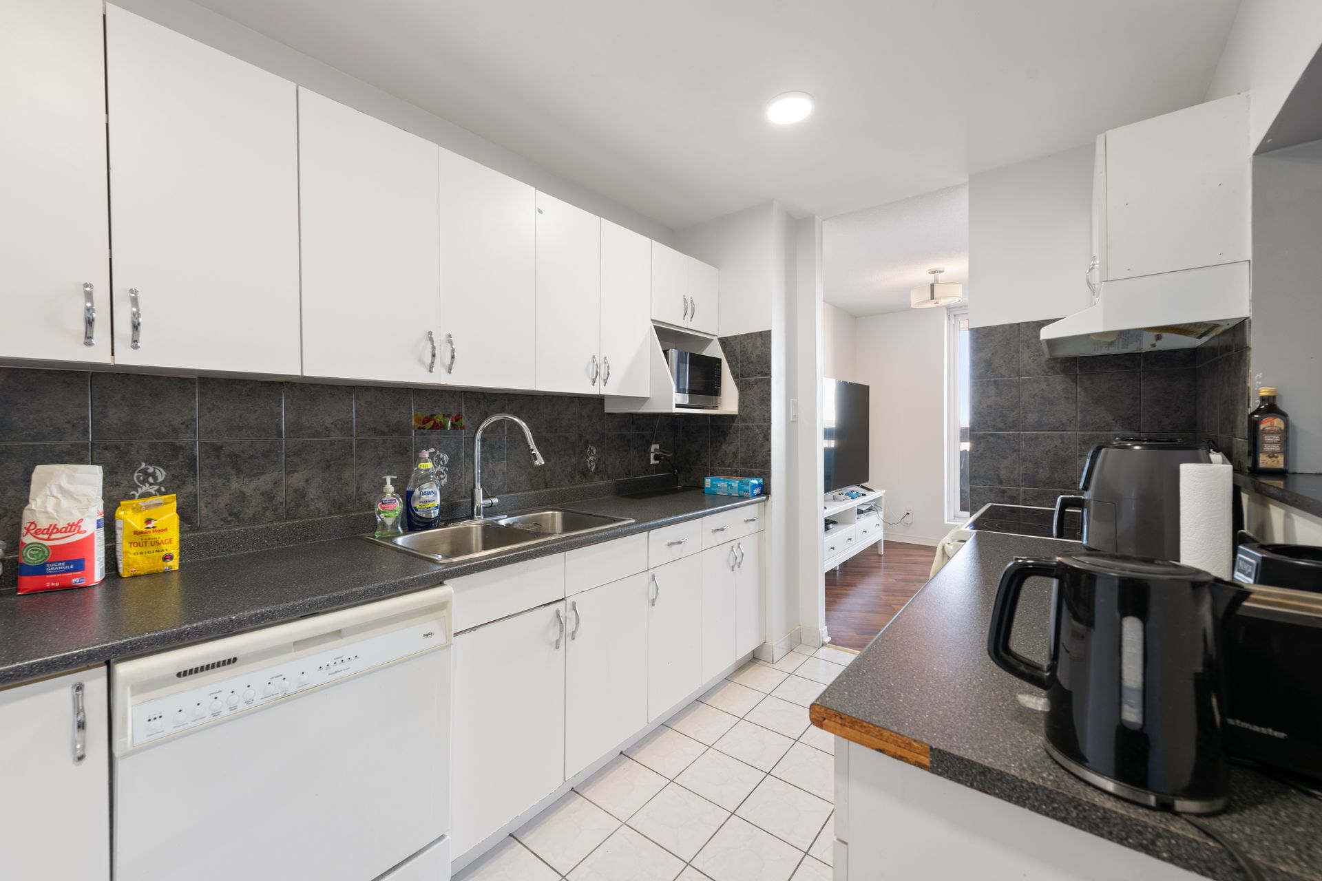 A kitchen with white cabinets and black counter tops
