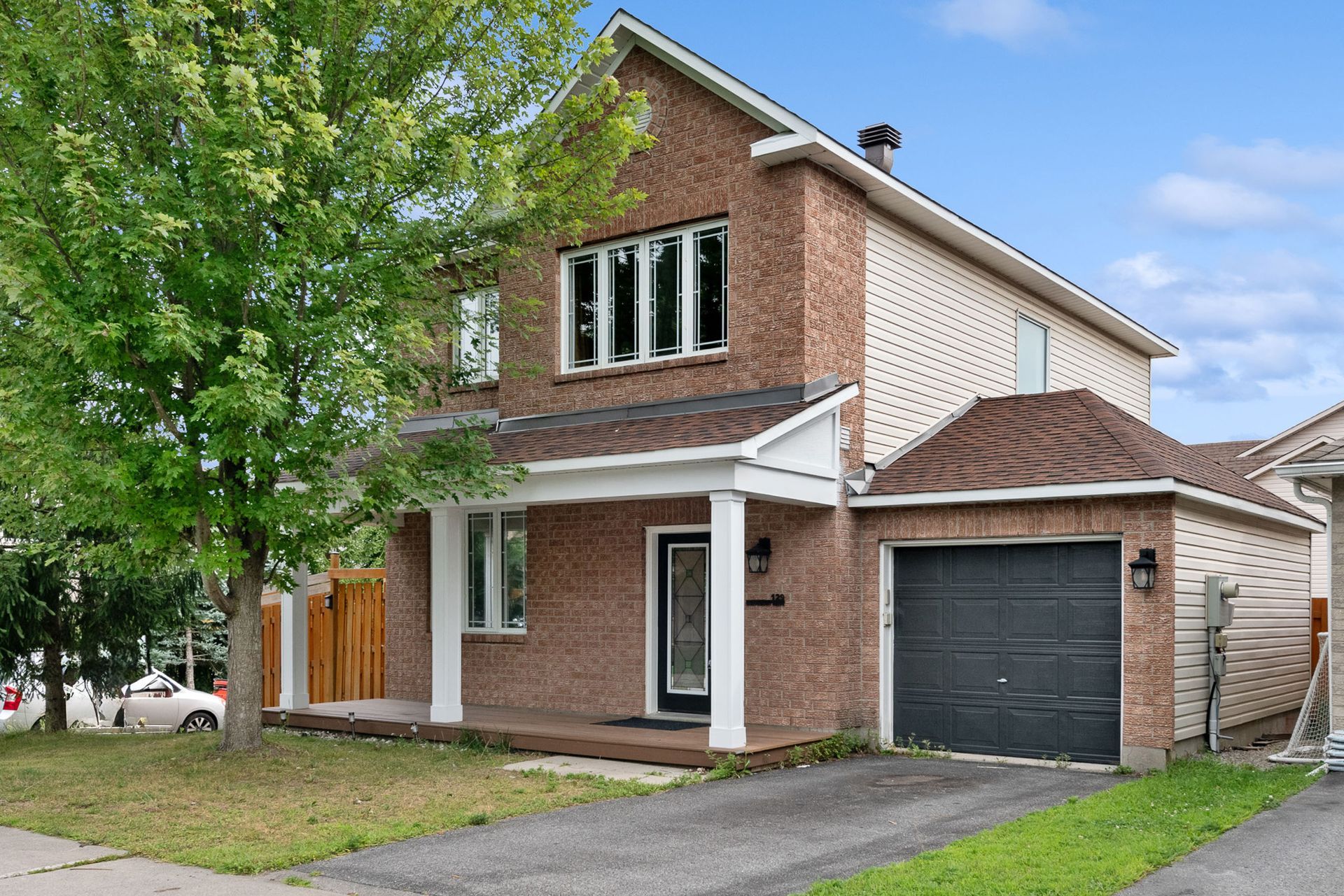 A brick house with a black garage door and a car parked in front of it.