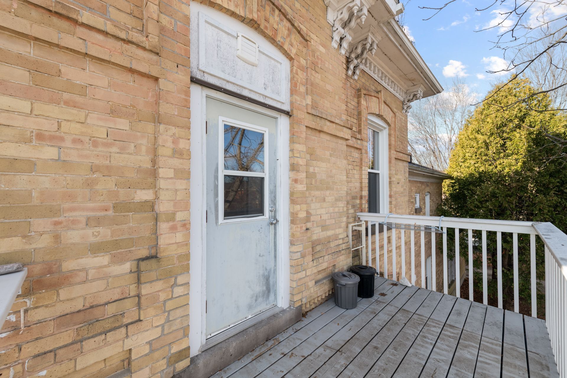 A brick building with a white door and a wooden deck.