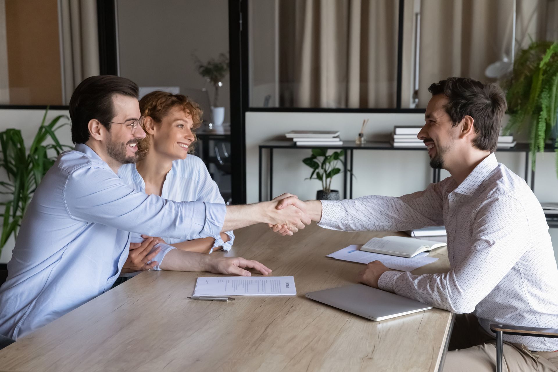 A man and a woman are shaking hands while sitting at a table.