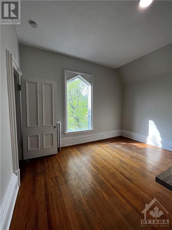 An empty room with hardwood floors and a large window.