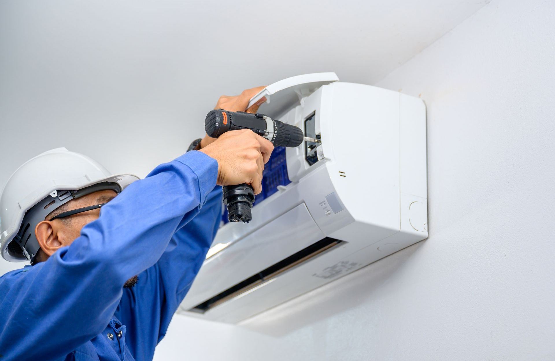 Un homme installe un climatiseur sur un mur.