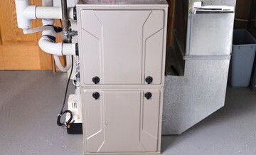 Fournaise avec deux panneaux beiges superposés et conduits d'aération intégrés, installée dans un sous-sol.