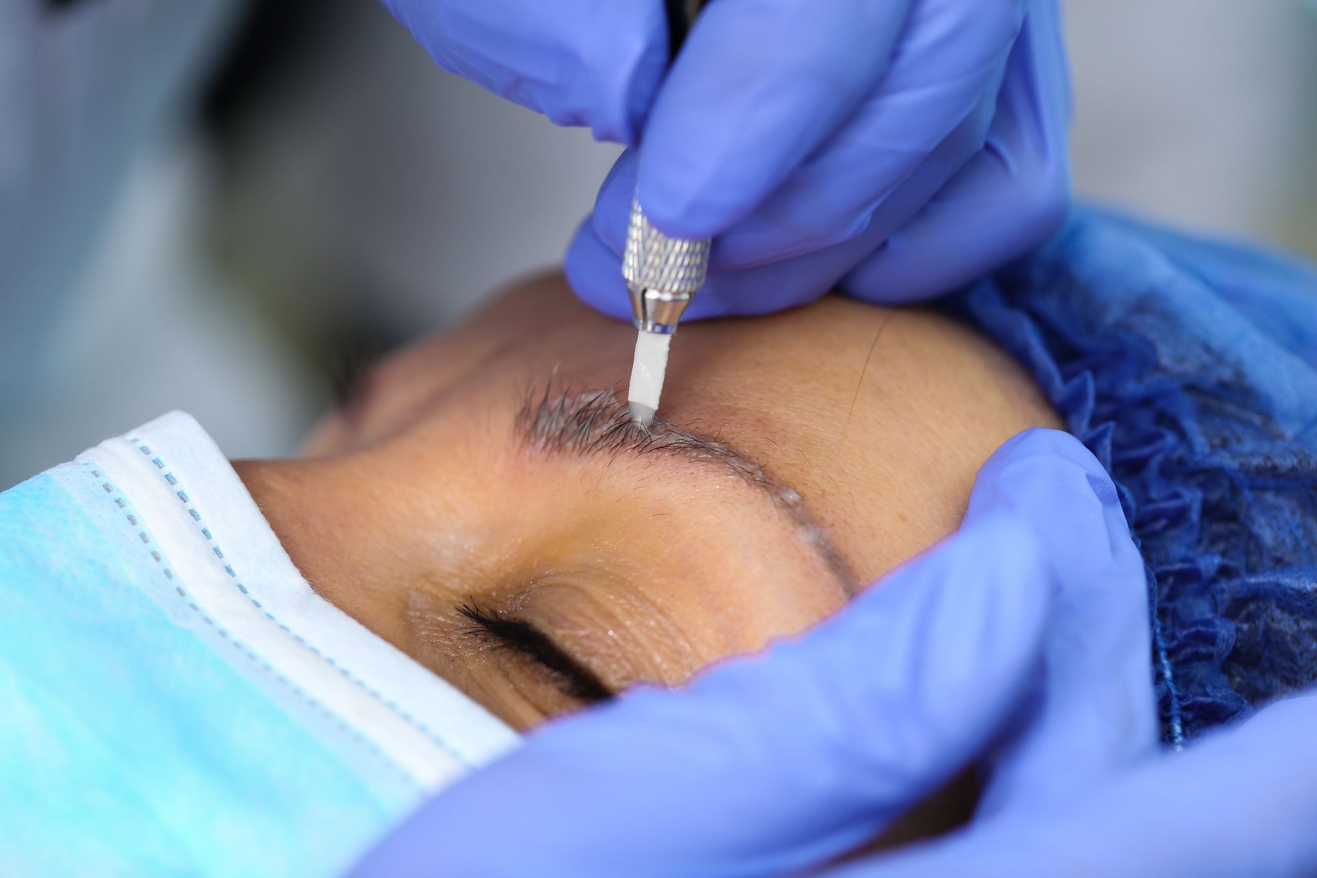 Mit behandschuhten Händen wird mithilfe eines kleinen Instruments eine kosmetische Behandlung