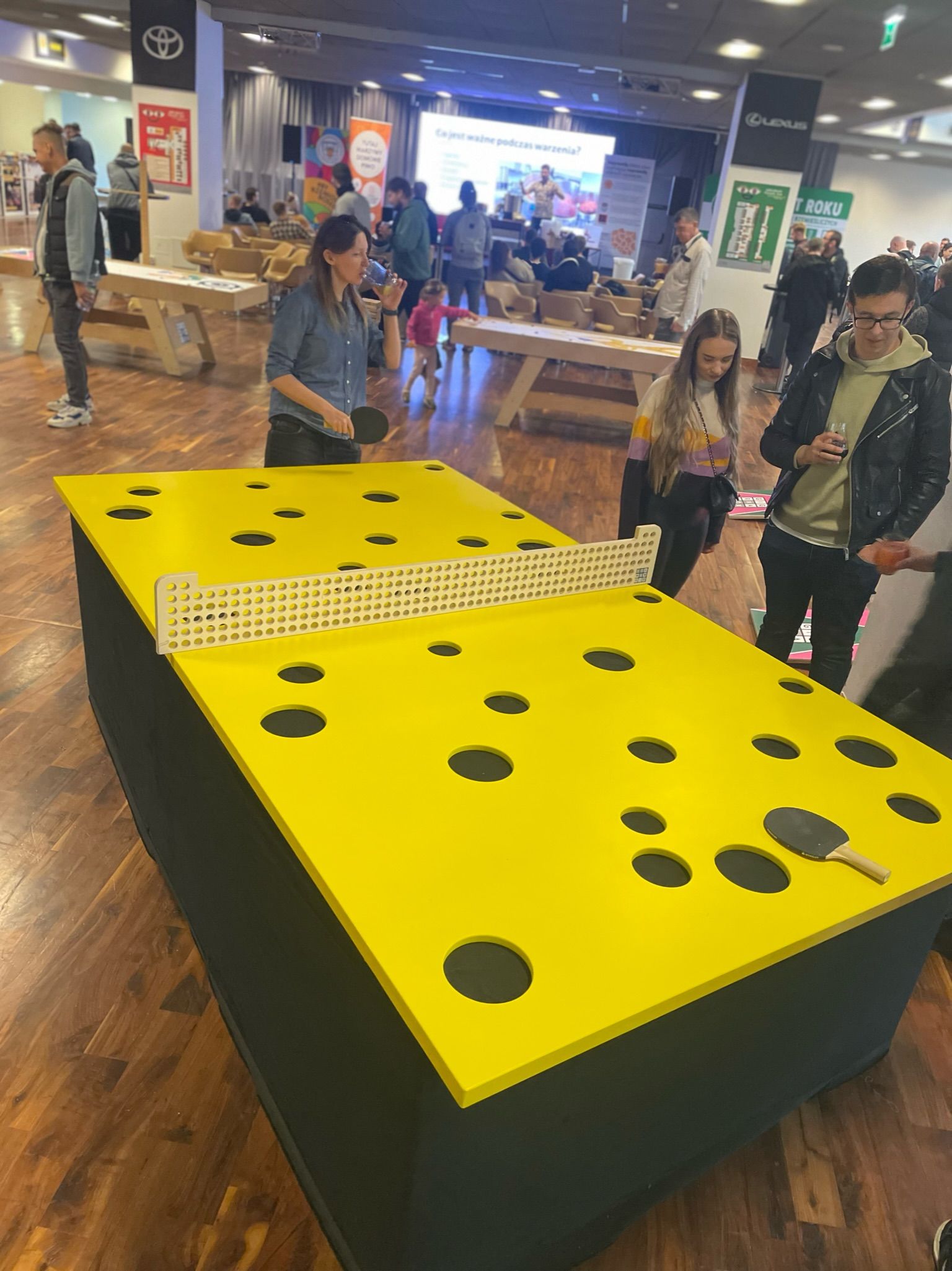 ludzie grają w ping-ponga na stole wyglądającym jak kawałek sera