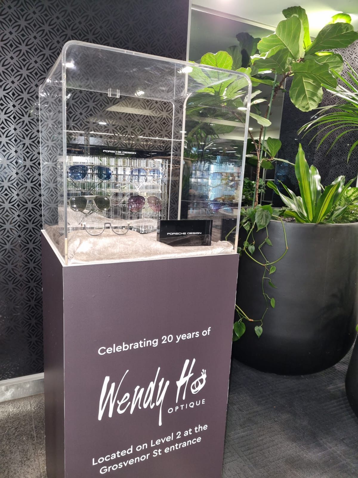 Display case for Wendy Ho Optique celebrating 20 years, with glasses inside, located on Level 2, Grosvenor St entrance.