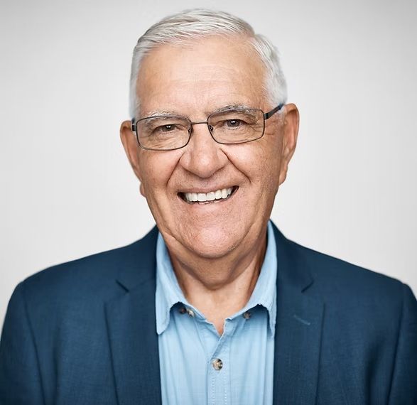 Smiling man with glasses, light blue shirt, and navy blazer.