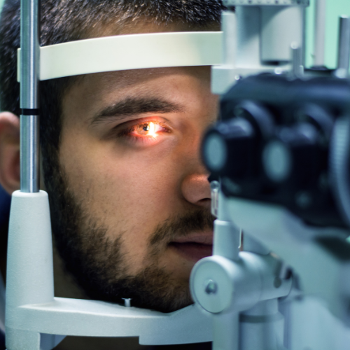 Man undergoing eye examination with a slit lamp, eye illuminated, close-up.