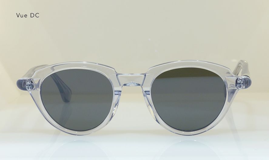 Clear-framed sunglasses with dark gray lenses on a white surface.