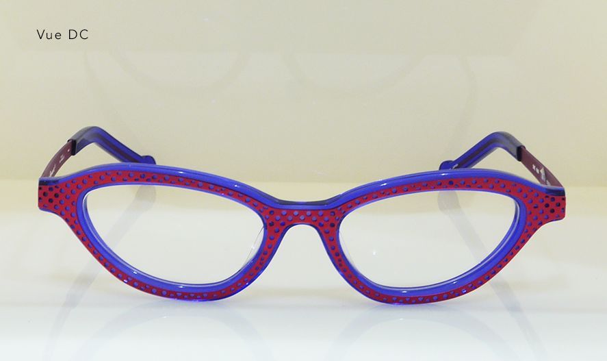 Purple and blue eyeglasses with a dotted frame, set against a light background.