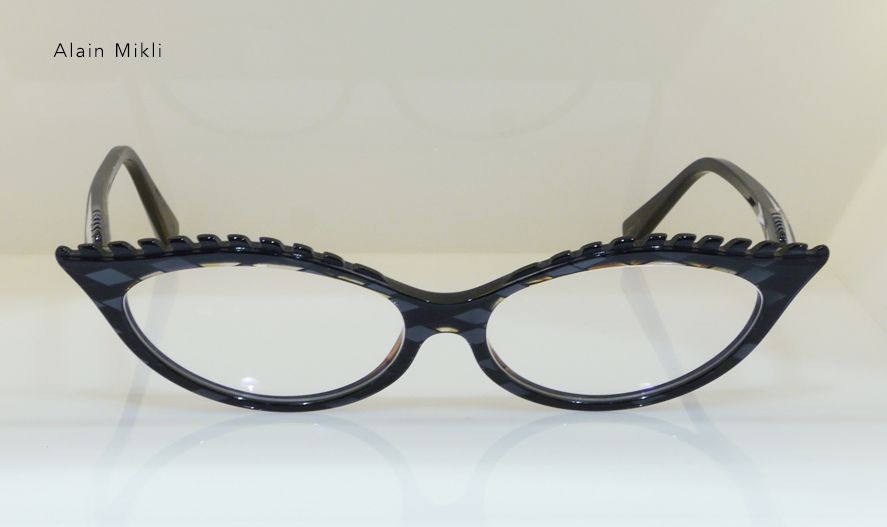 Black cat-eye glasses with decorative trim and clear lenses, on a reflective surface.