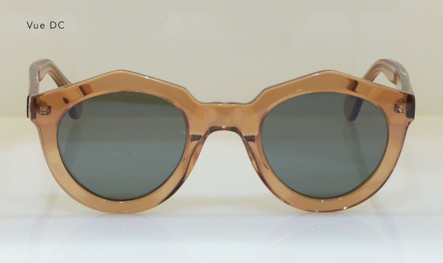 Brown-framed sunglasses with round lenses on a light surface.