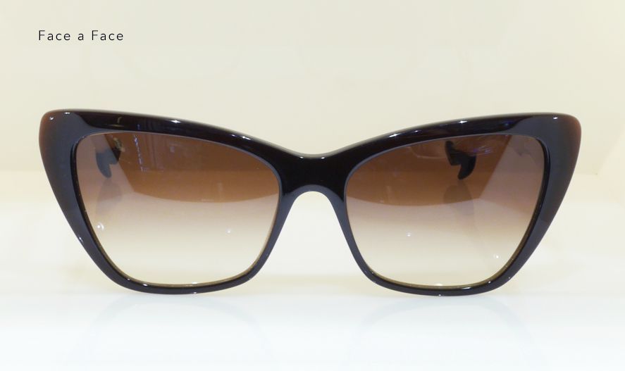Black cat-eye sunglasses with brown gradient lenses, against a neutral backdrop.