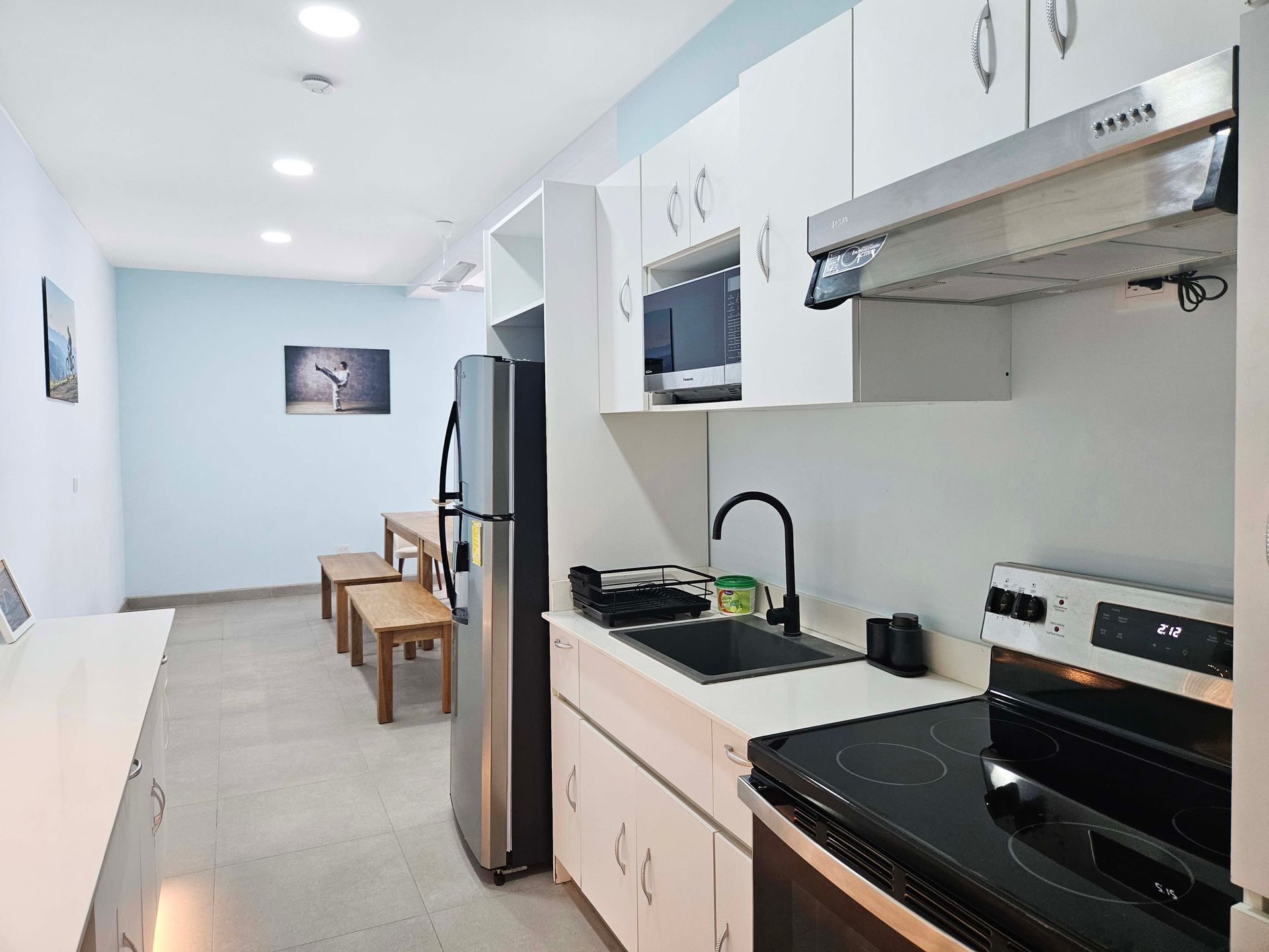 A small apartment kitchen with white cabinets, stainless steel appliances, and a light blue wall.
