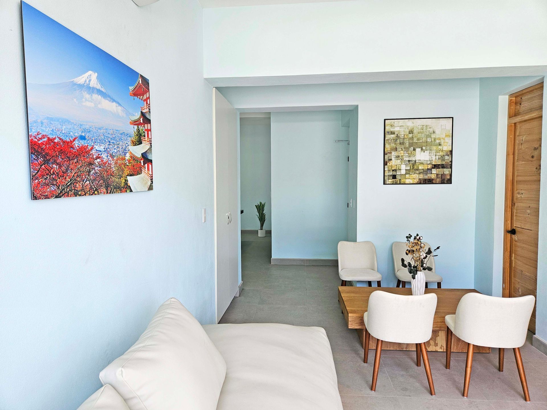Living room with light blue walls, art, and a small dining area.