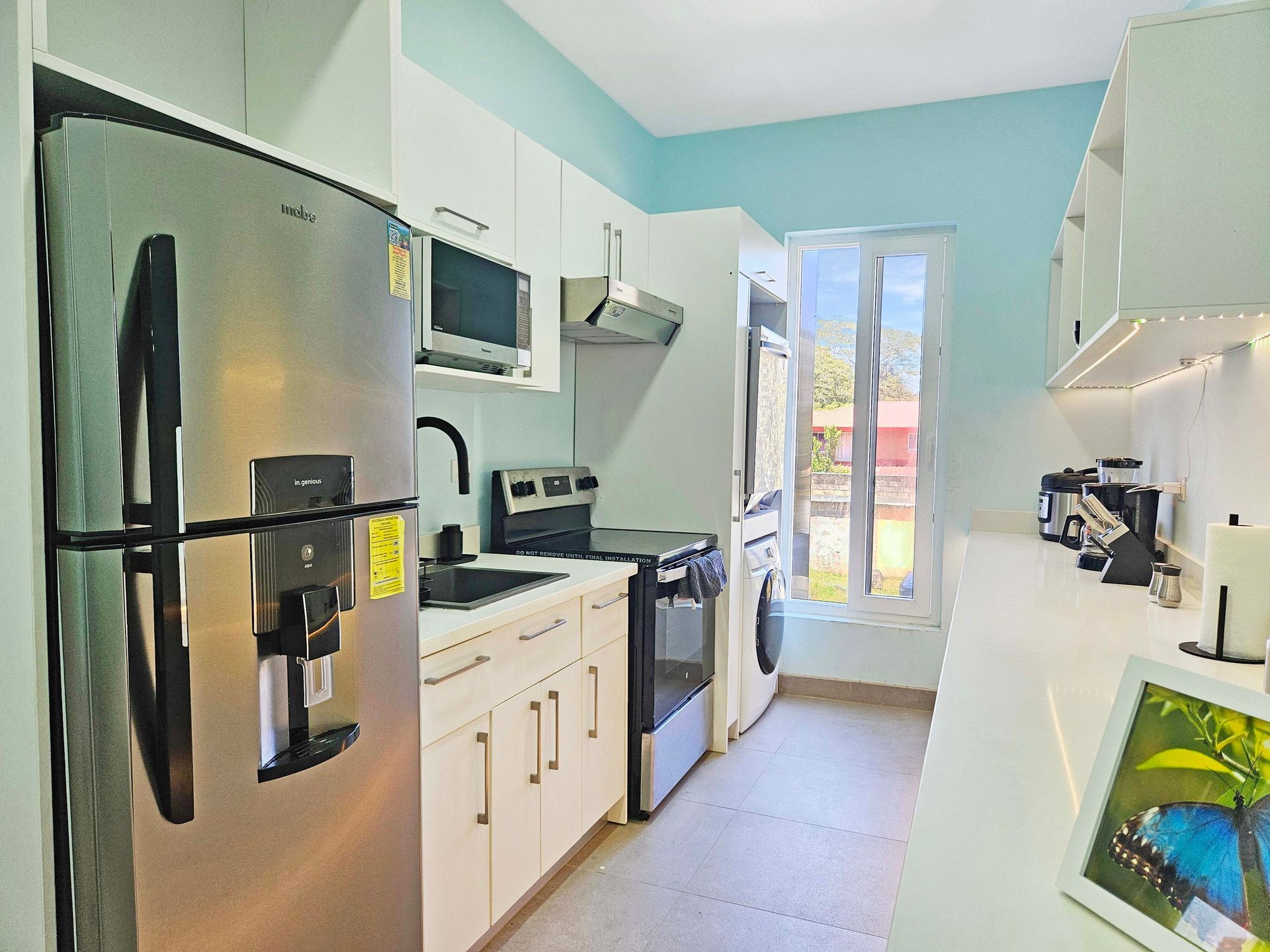 Small kitchen with white cabinets, stainless steel appliances, and a window.