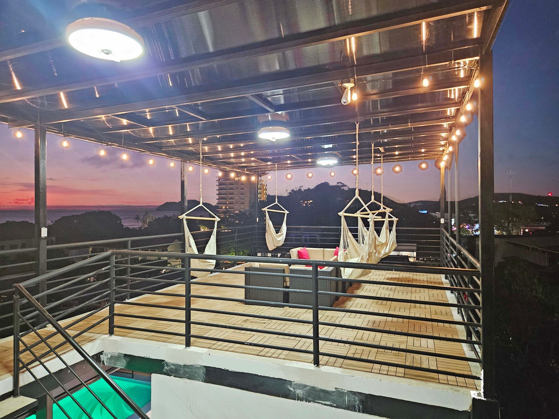 Rooftop deck with swings, string lights, and sunset view.