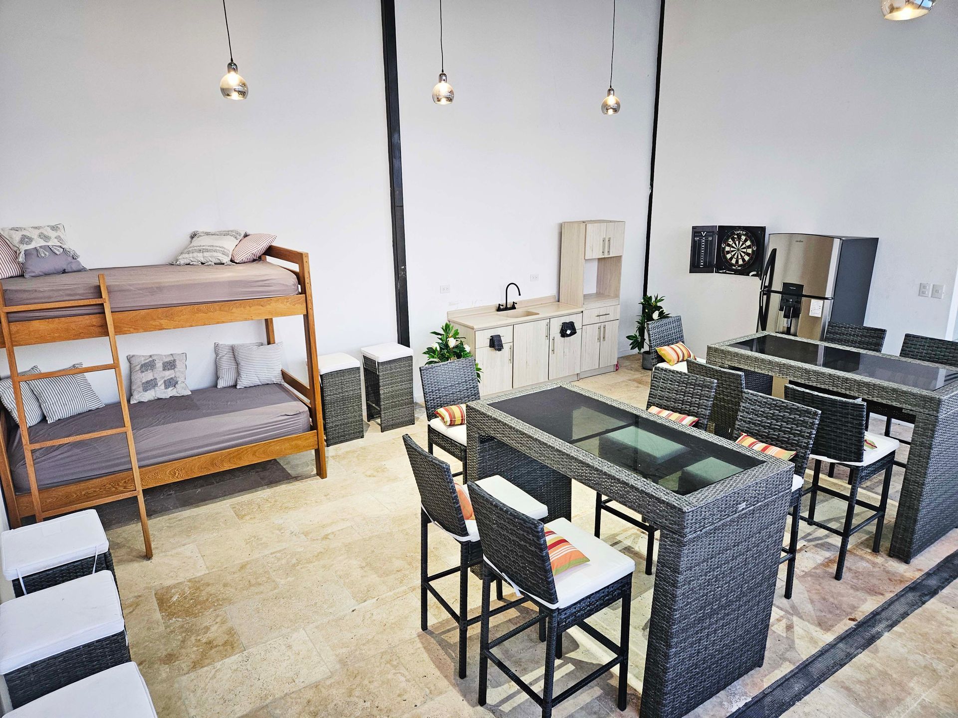 Interior with bunk beds, kitchen, and bar tables with stools. Bright, modern space with neutral colors.