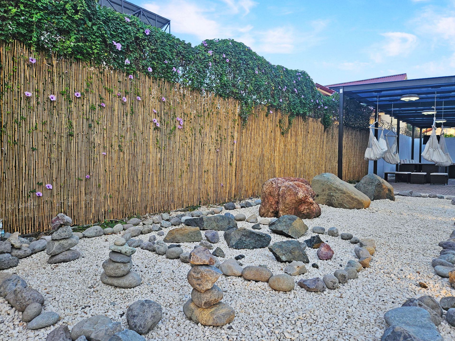 Zen garden with stone arrangements, bamboo fence, and white gravel.