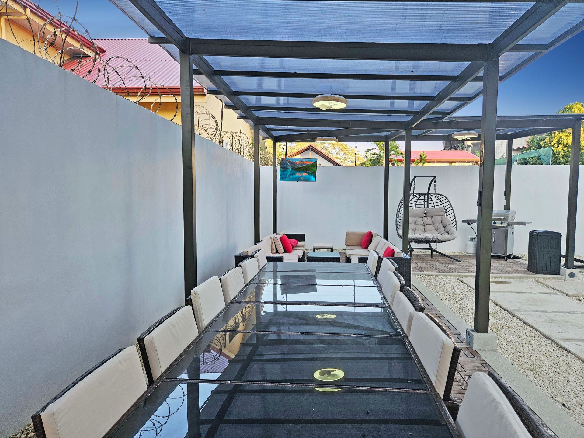 Outdoor dining area with long table, seating, pergola, and lounge area.
