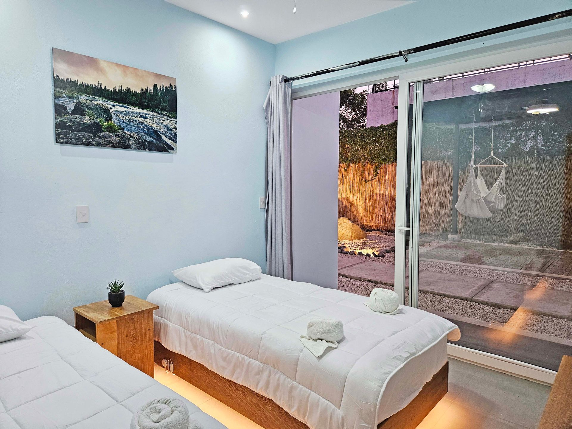 Bedroom with two twin beds, small wooden nightstand, and sliding glass door to a patio.