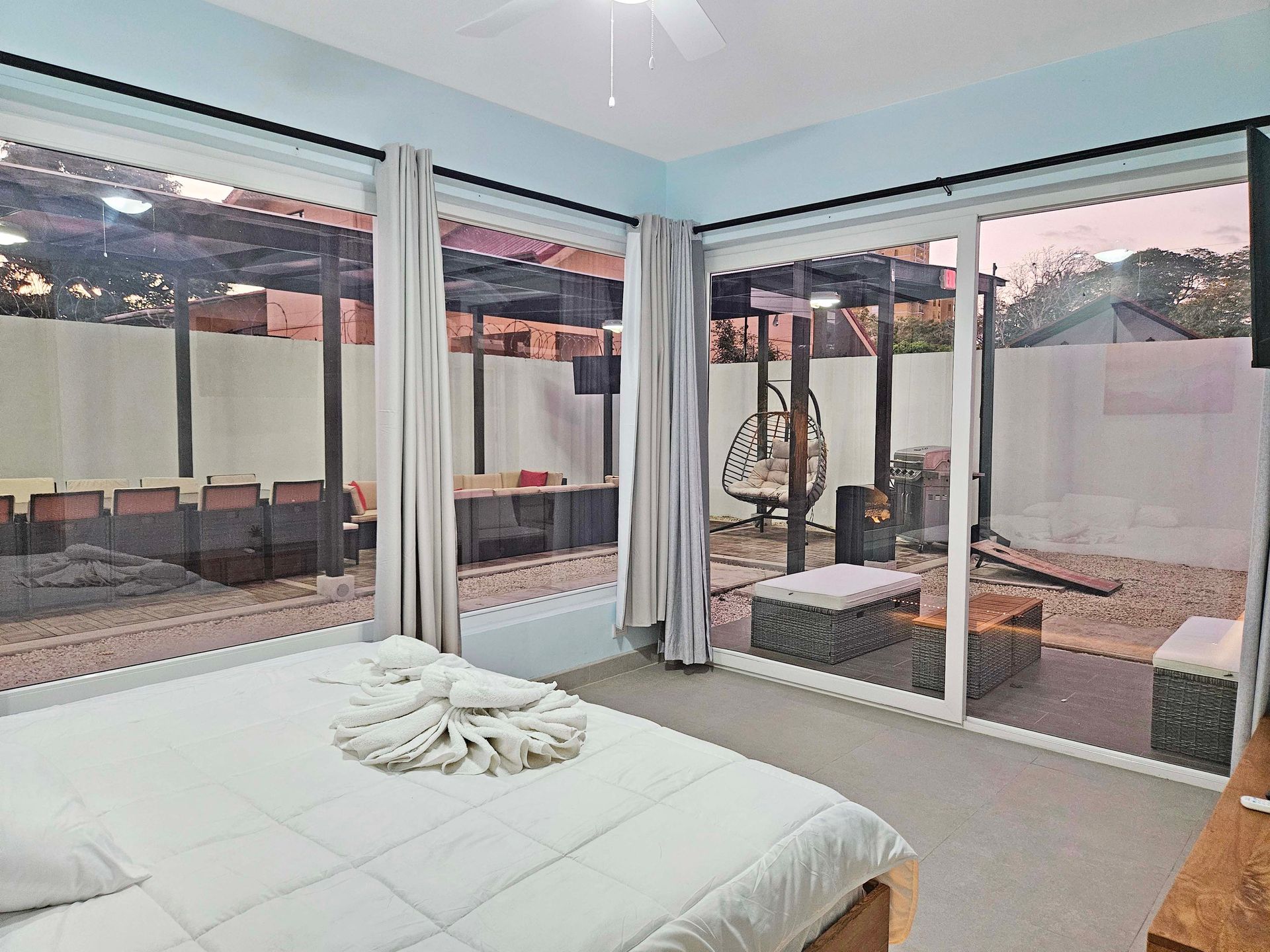 Bedroom with sliding glass doors overlooking an outdoor patio with seating and a hanging chair.