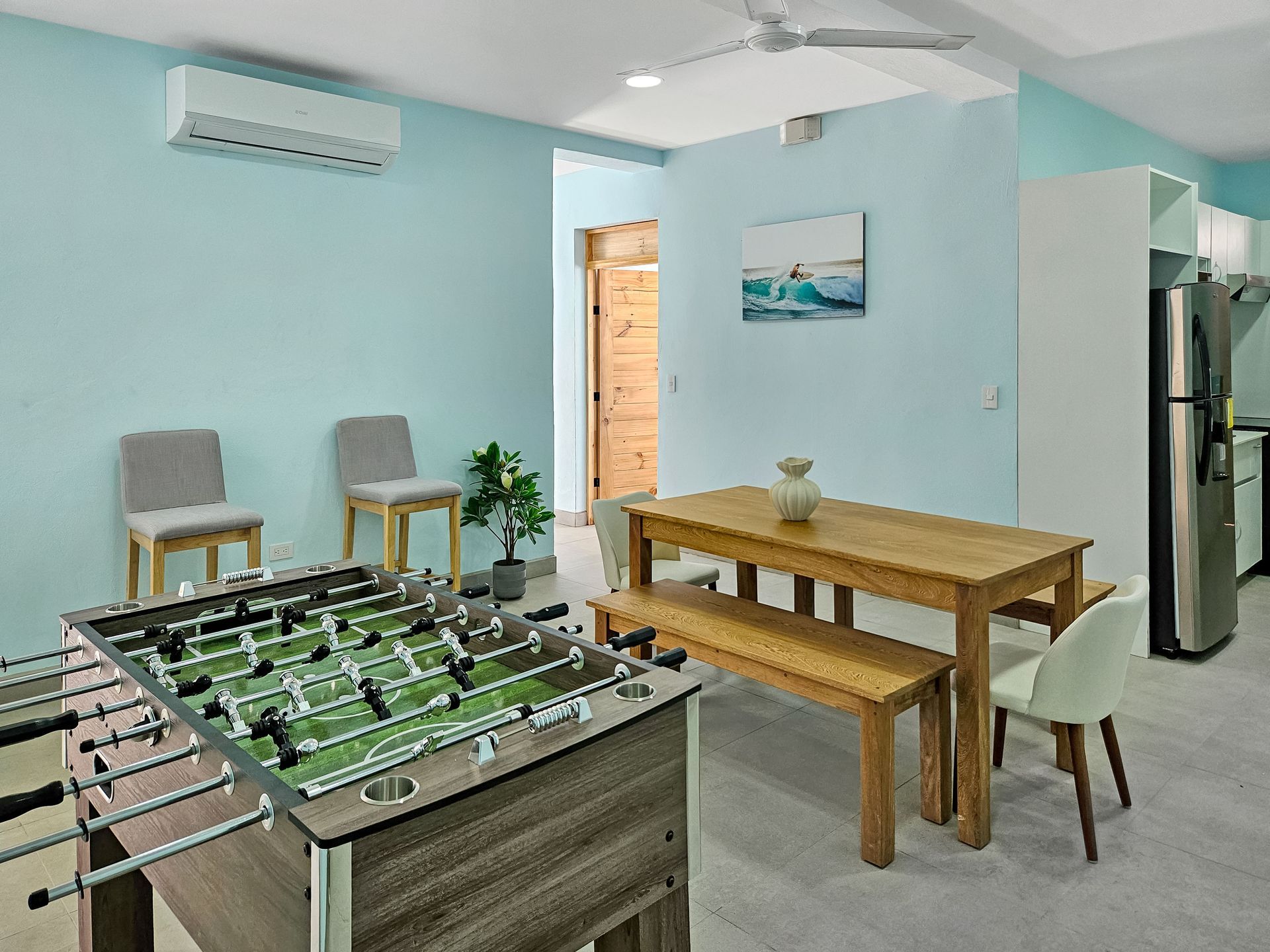Foosball table in a room with a dining table, chairs, and light blue walls.