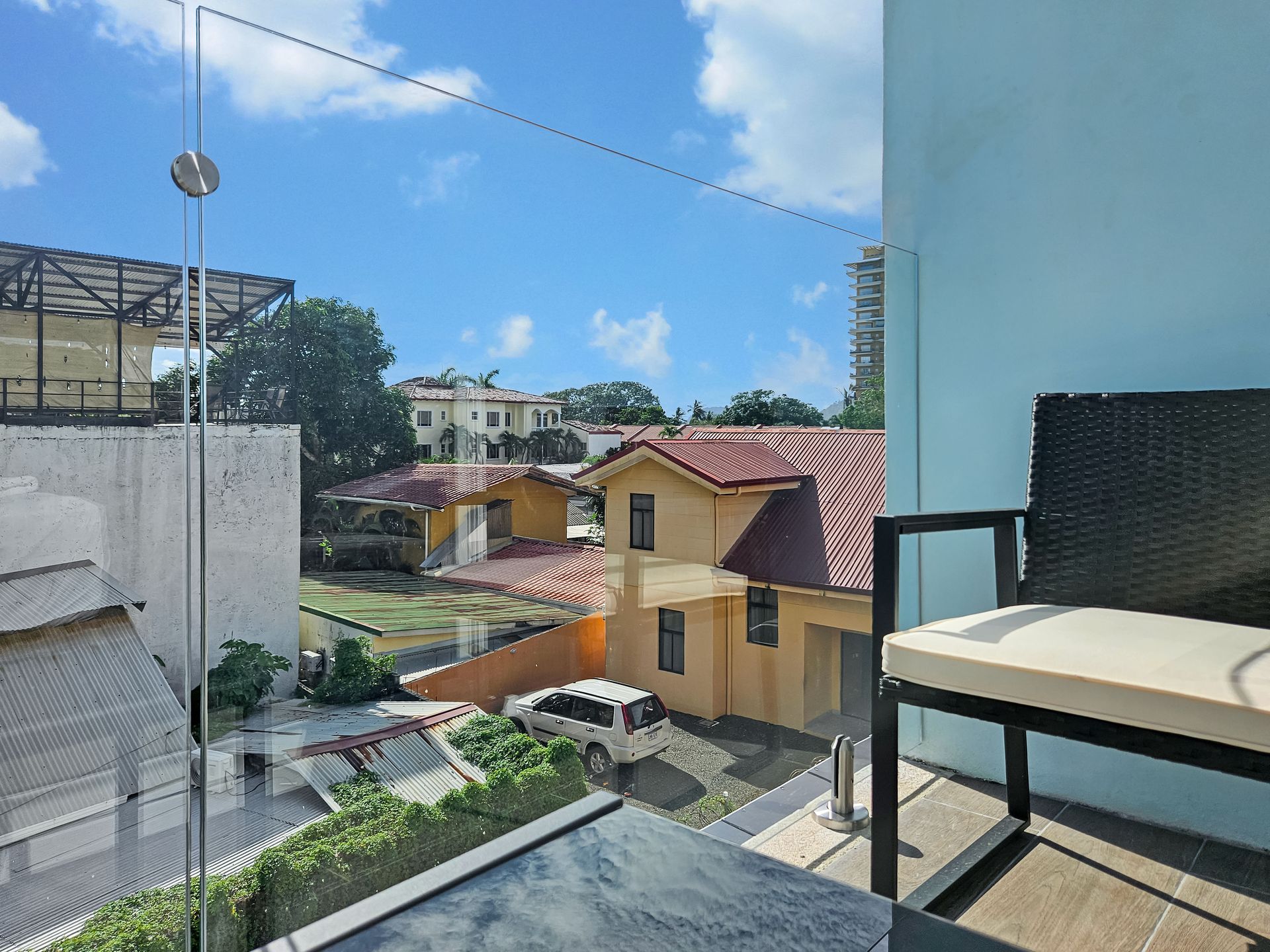 View of neighborhood with yellow houses, blue sky, and a patio chair.