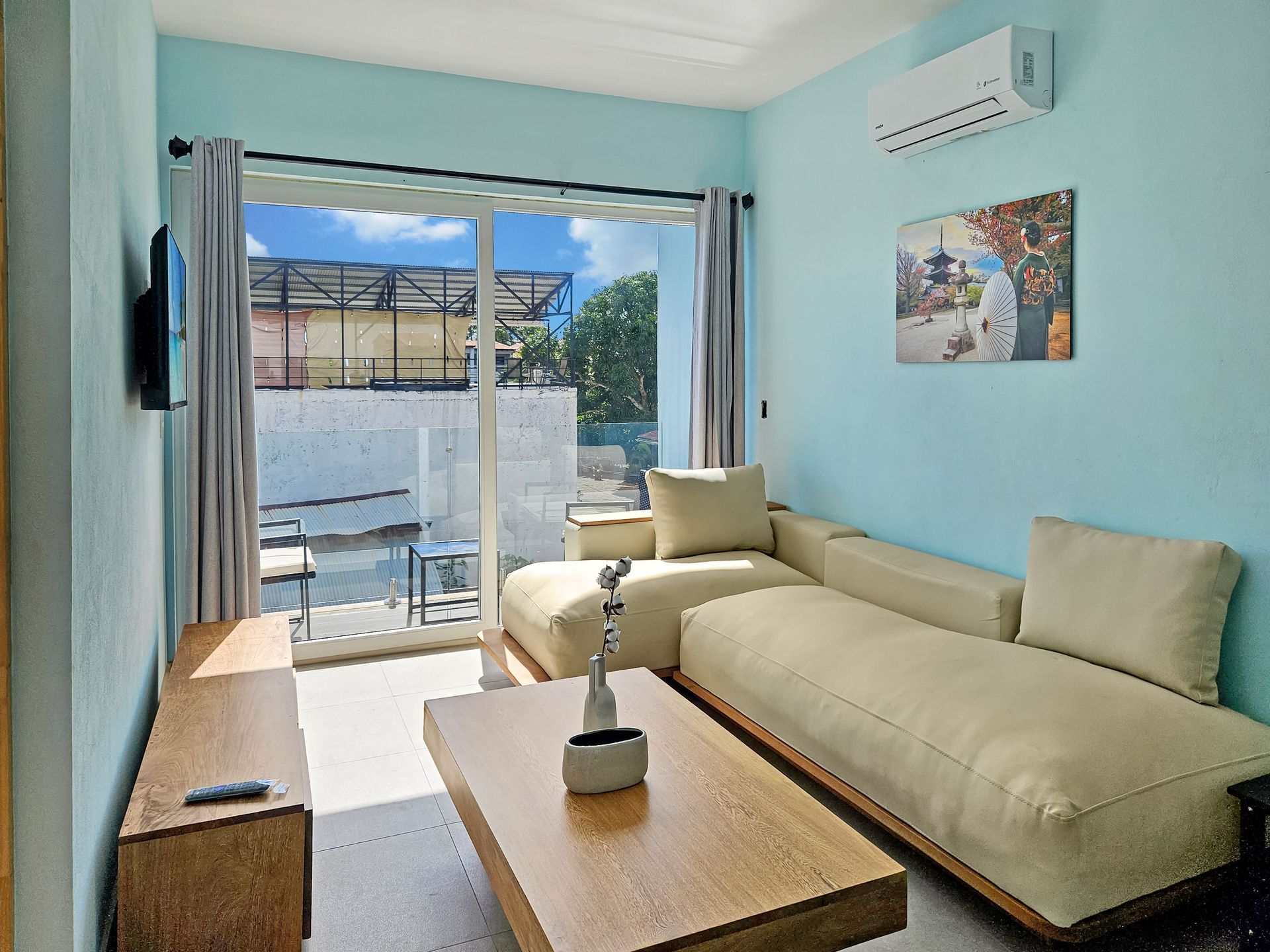 Living room with beige sectional sofa, sliding glass door to a balcony, and blue walls.