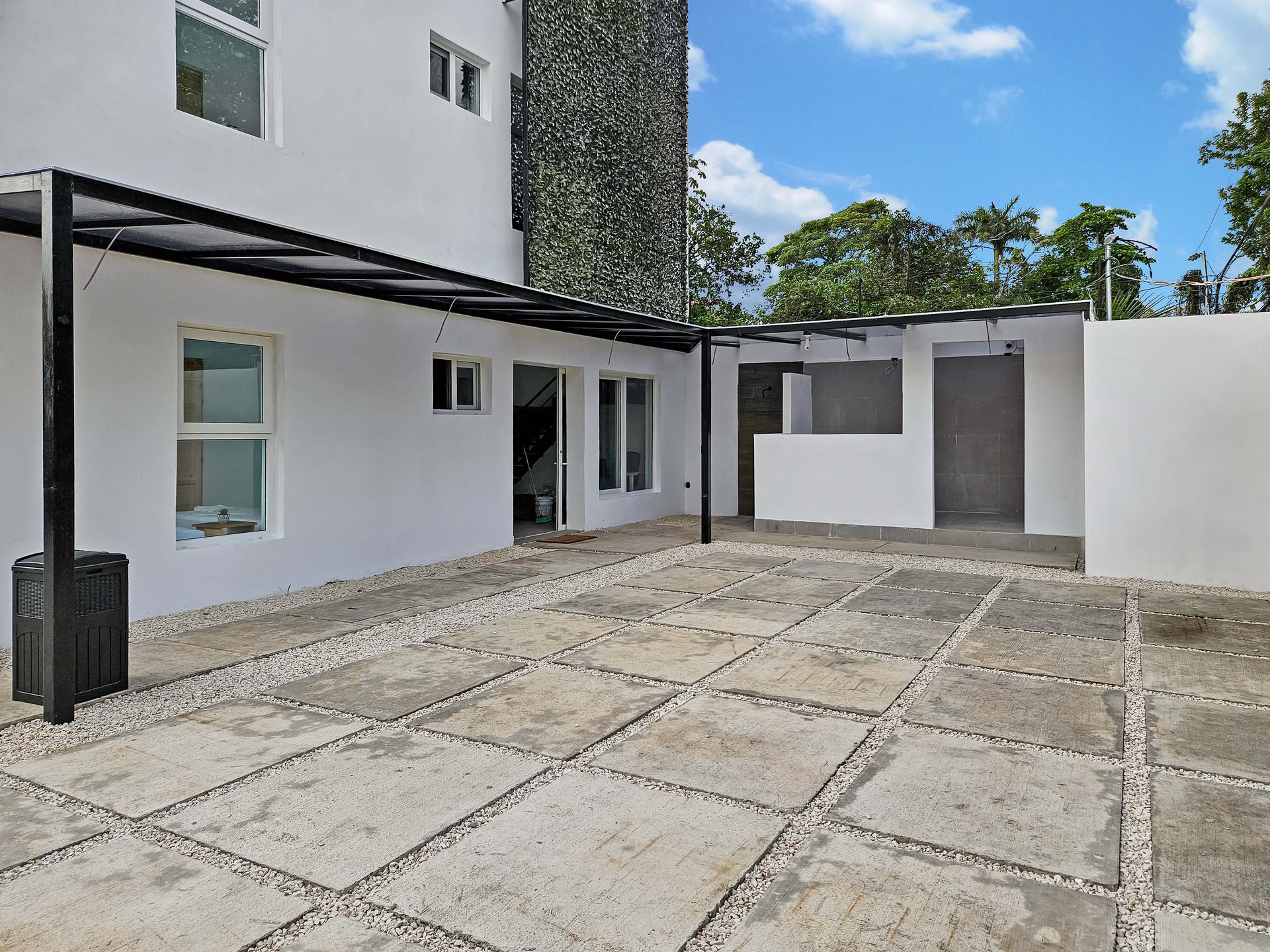 White building with covered patio and stone patio flooring.