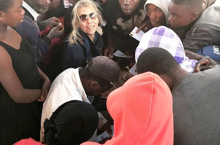 A group of people are gathered around a man in a white shirt