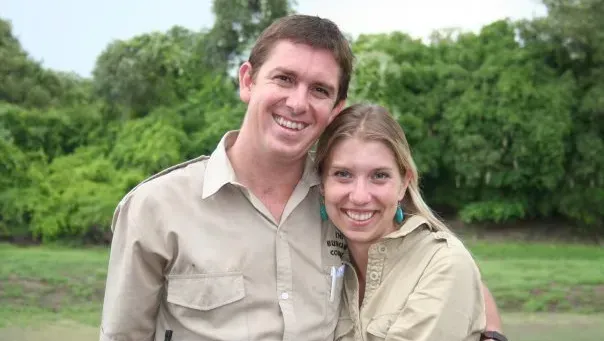 A man and a woman are posing for a picture in a field.