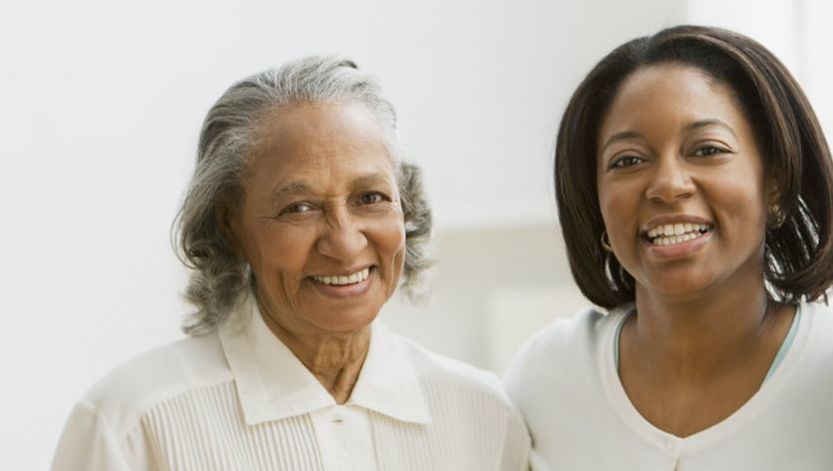 Two women are posing for a picture together and smiling for the camera.