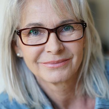 A close up of a woman wearing glasses and smiling.