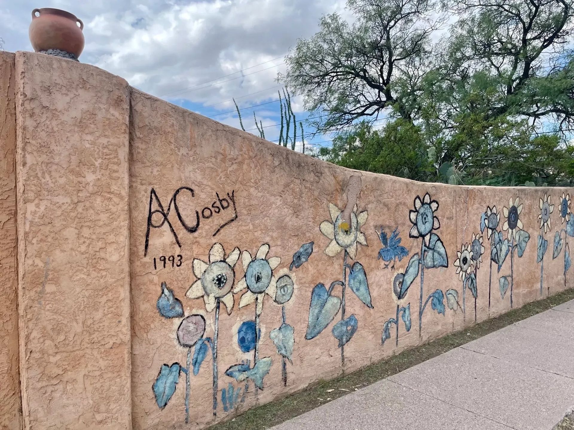 Beige stucco building with bell tower, arched windows, red tile roof, and blue sky.