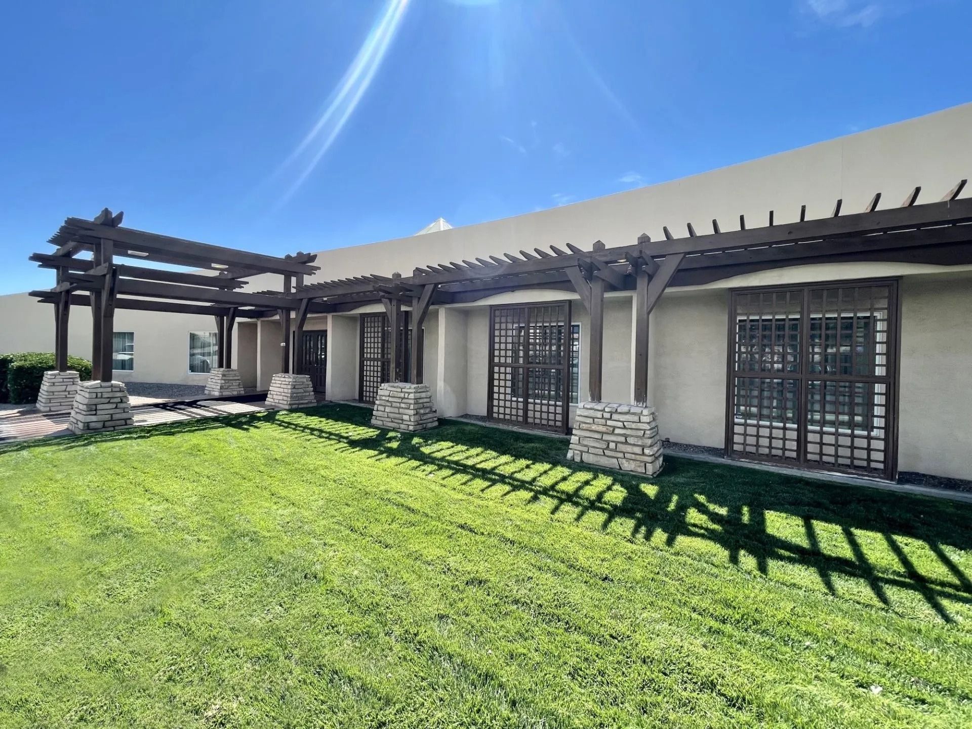Rendering of a memorial with a central cross and surrounding structures, trees, and sky.