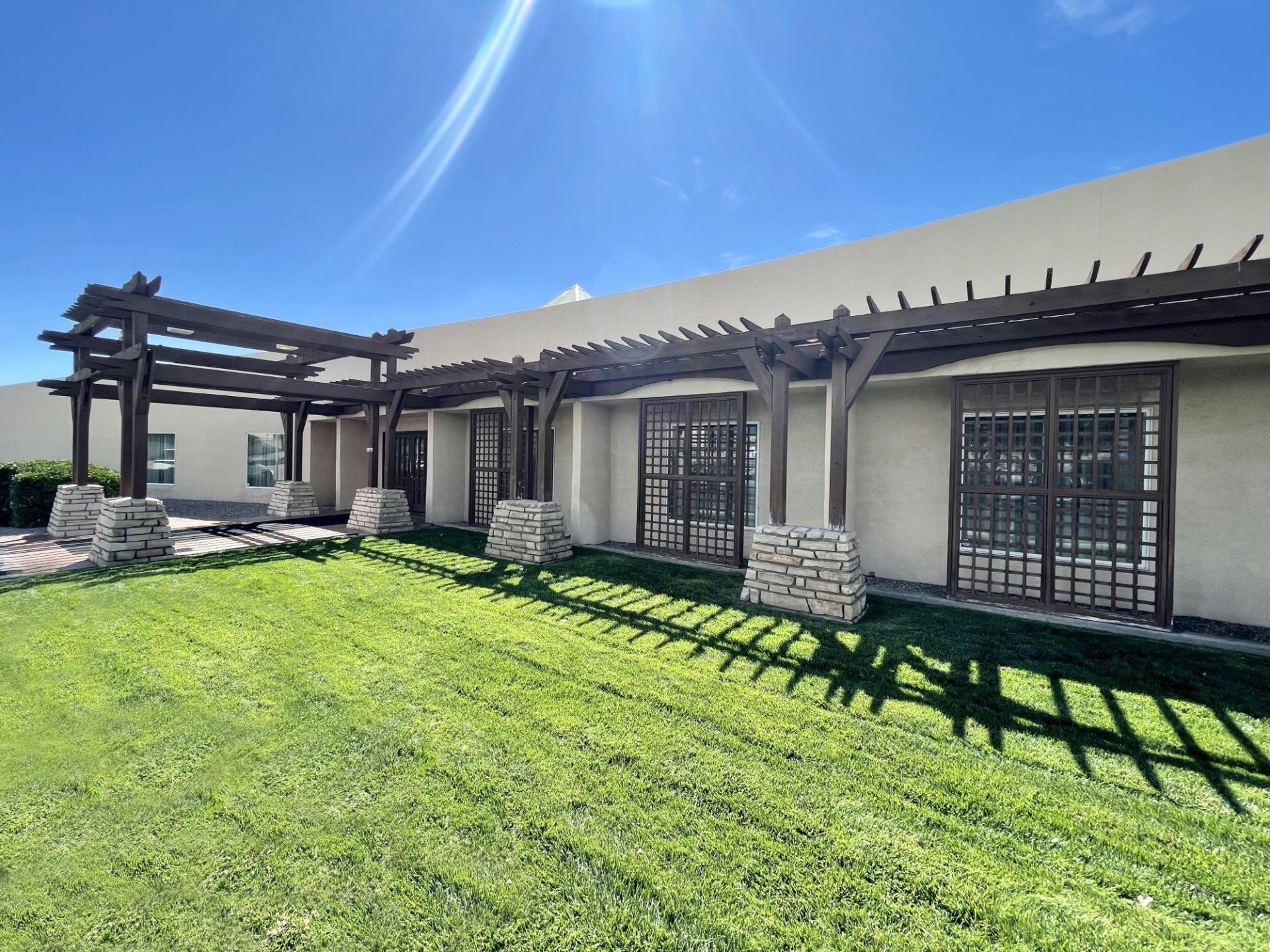 Beige stucco building with bell tower, arched windows, red tile roof, and blue sky.