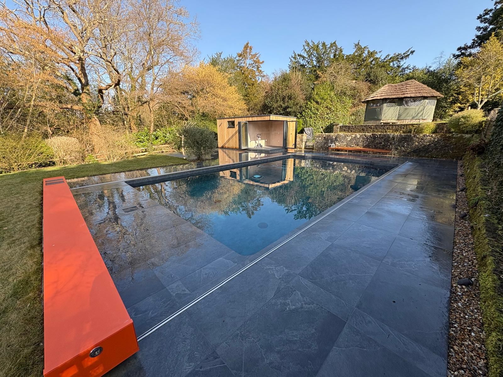 A large swimming pool is surrounded by trees and grass in a backyard.