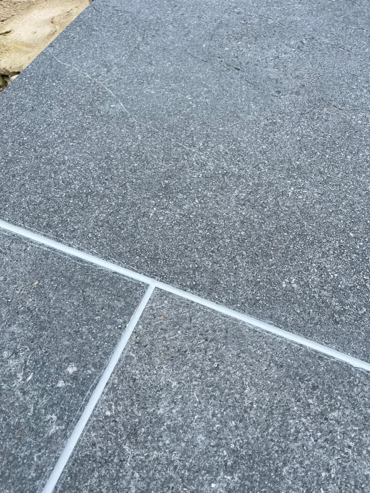 A close up of a concrete floor with a white line between the tiles.