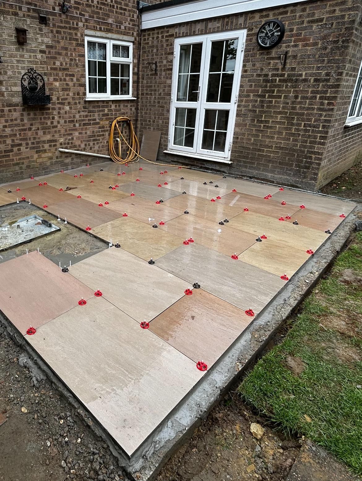 A patio is being built in front of a brick house.