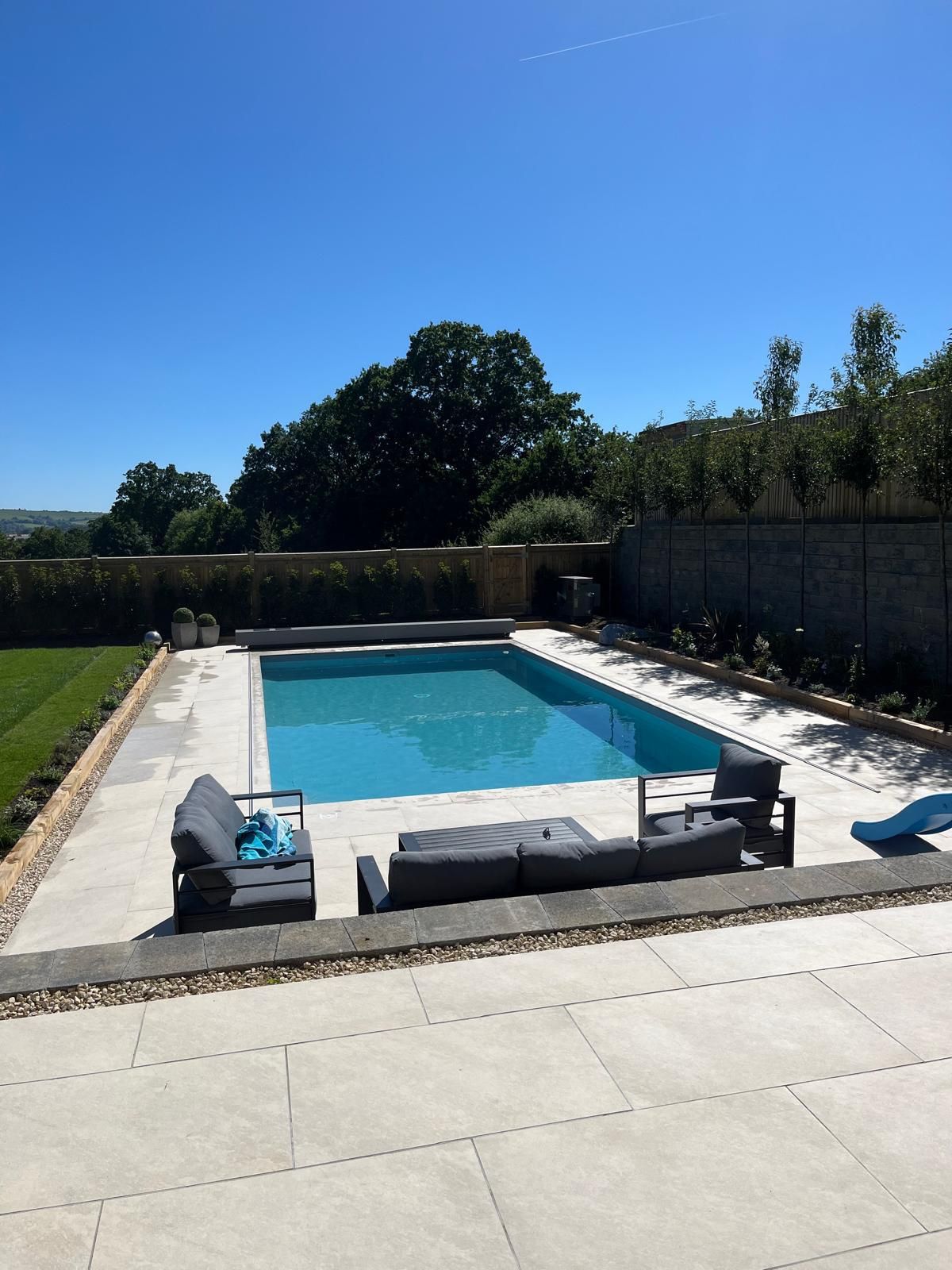 A large swimming pool is surrounded by a patio area