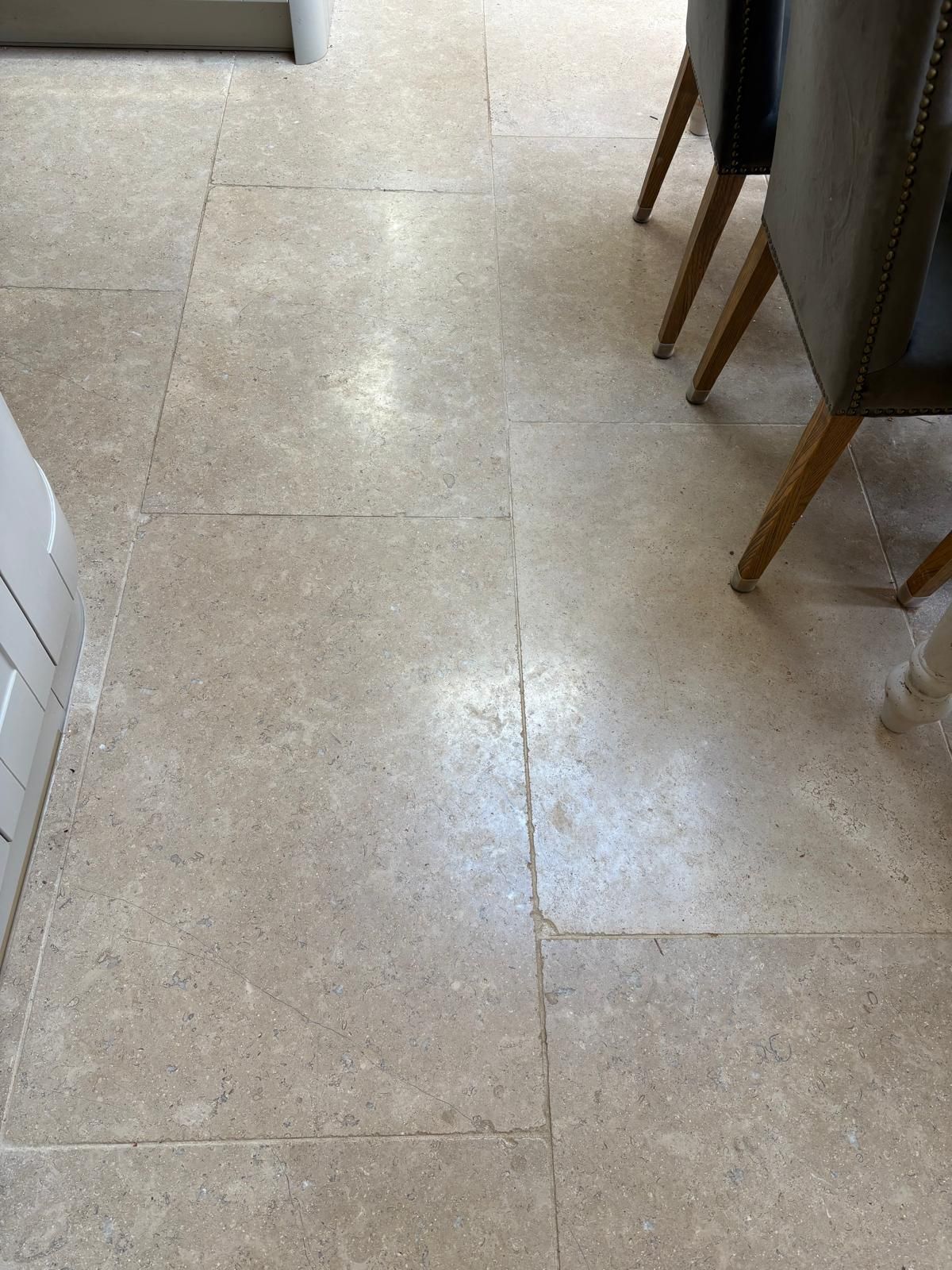 A close up of a tiled floor in a kitchen with chairs.