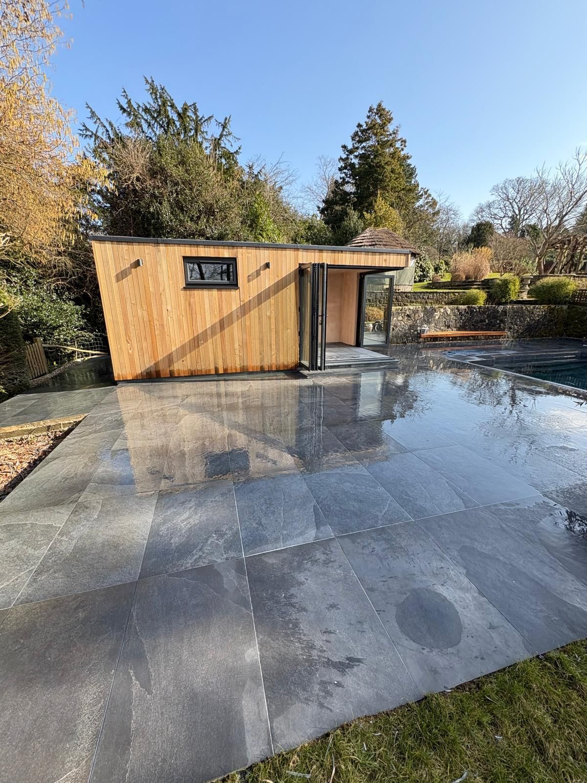 A wooden house is sitting next to a swimming pool.