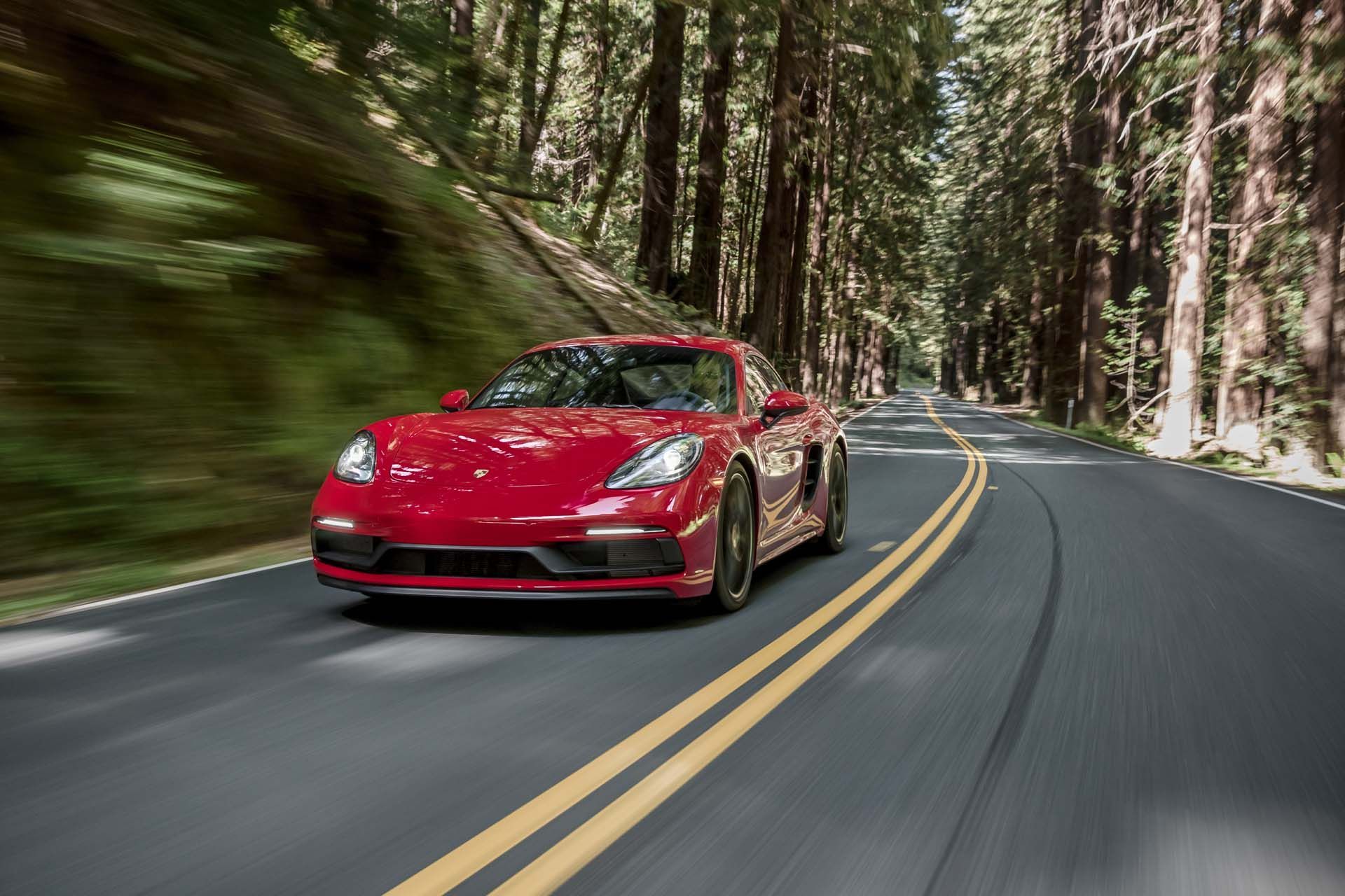 A man is wrapping a red car with a protective film.