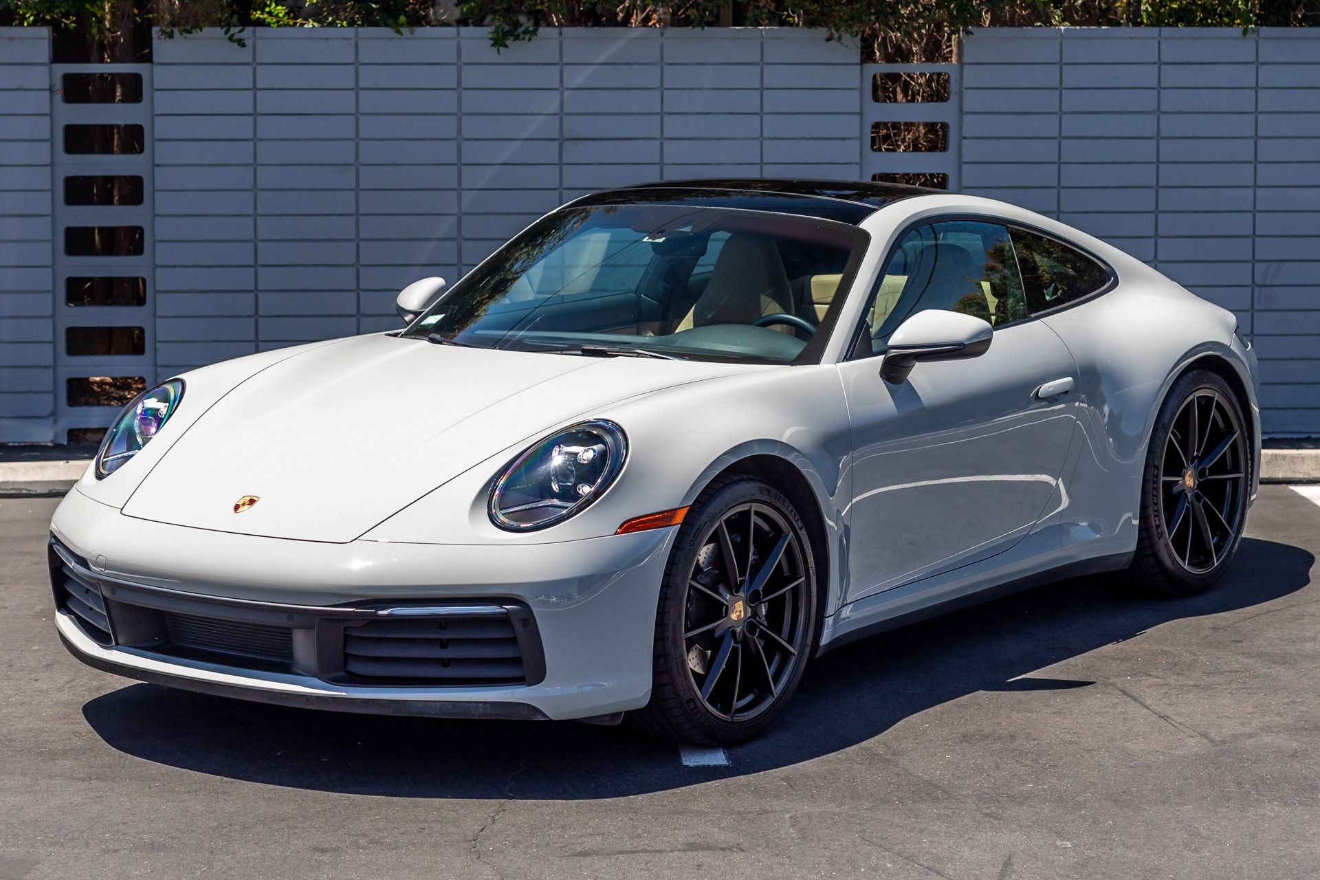 A man in a green shirt is applying a film to the roof of a car.