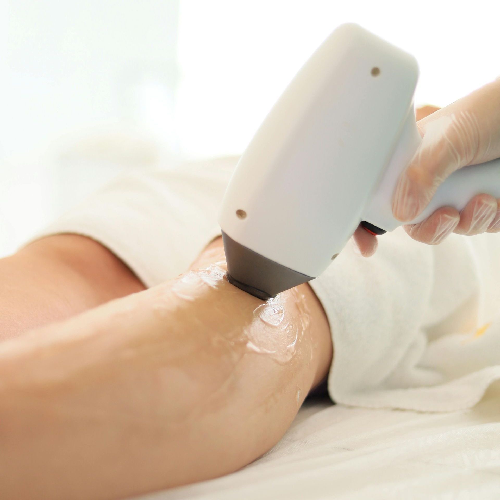 Laser hair removal treatment on a leg; the technician is using the device to remove unwanted hair.