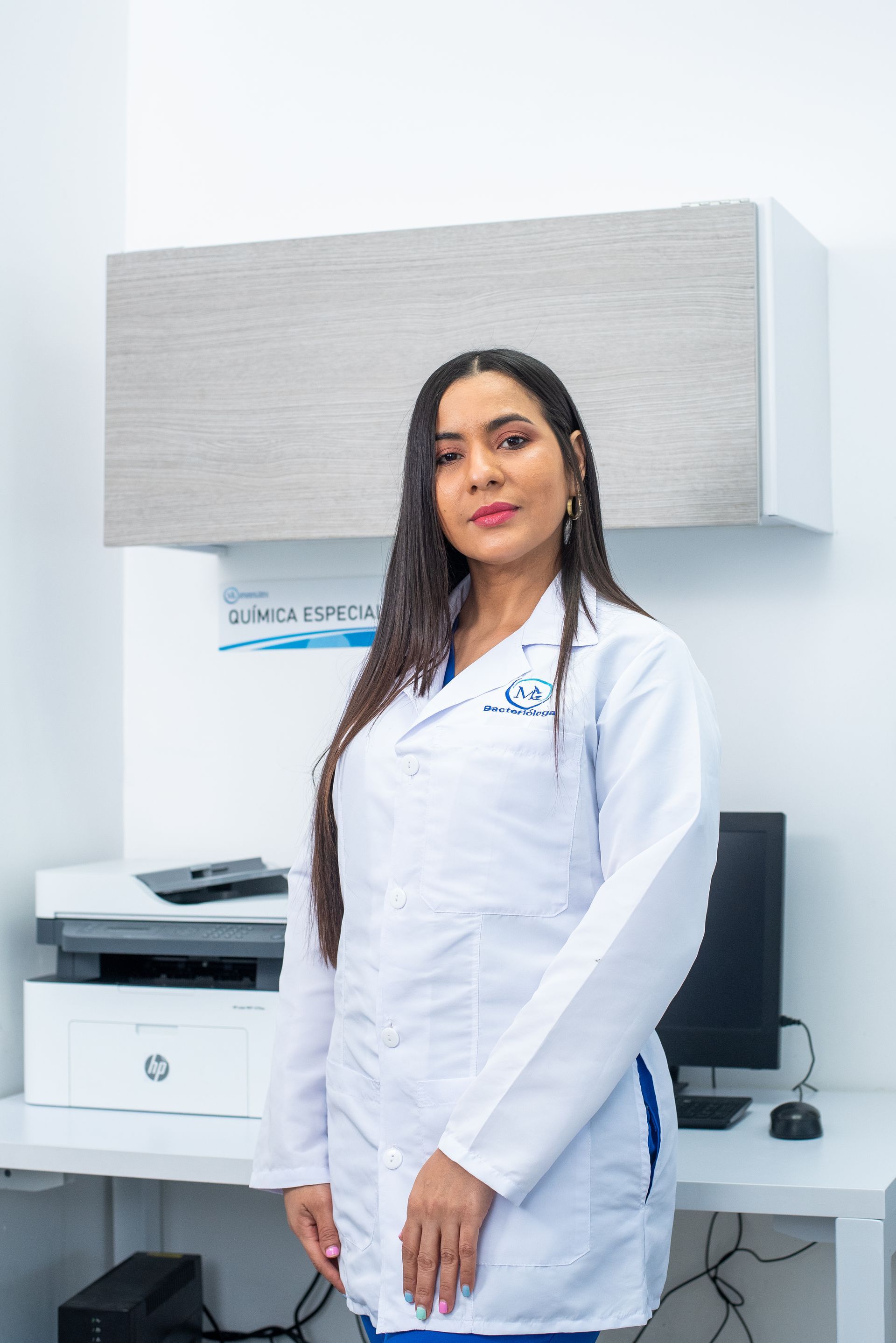 Una mujer con una bata blanca está parada frente a una computadora.