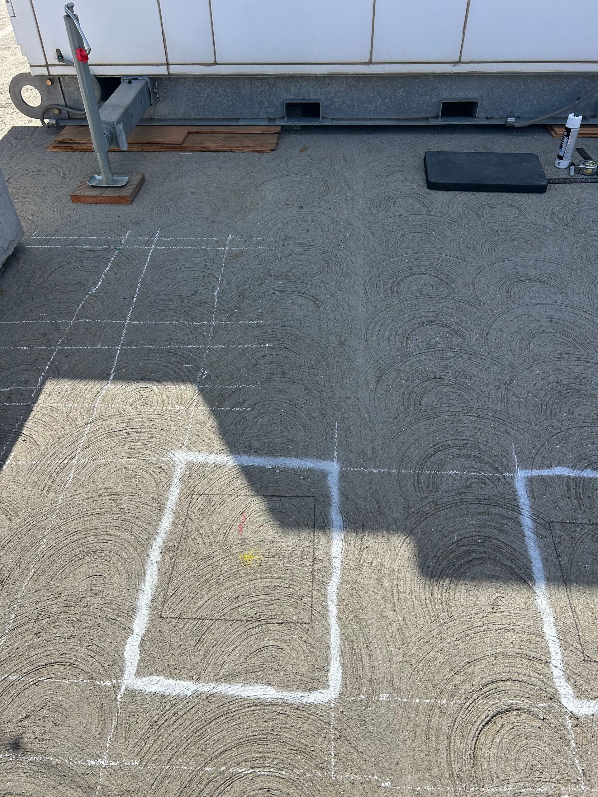 White chalk lines on asphalt, outlining shapes, near a trailer.