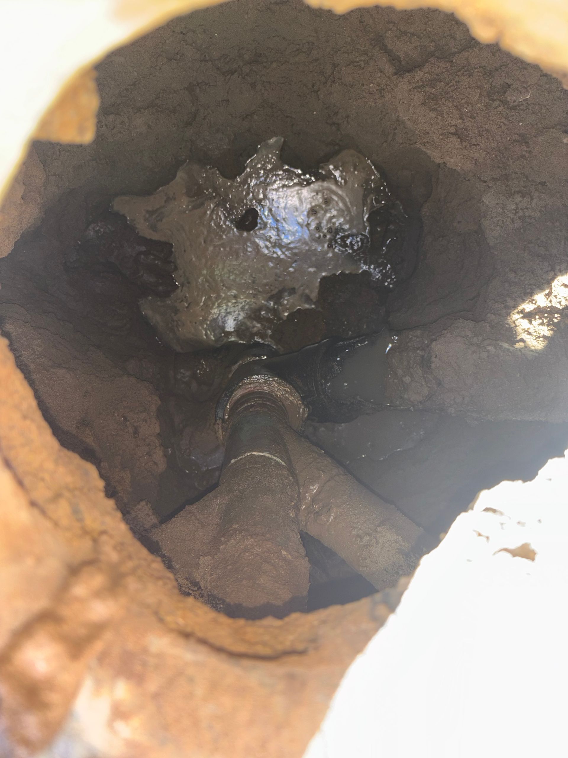 Inside of a cylindrical structure; dark, wet substance surrounds metal pipes and a partially visible object.