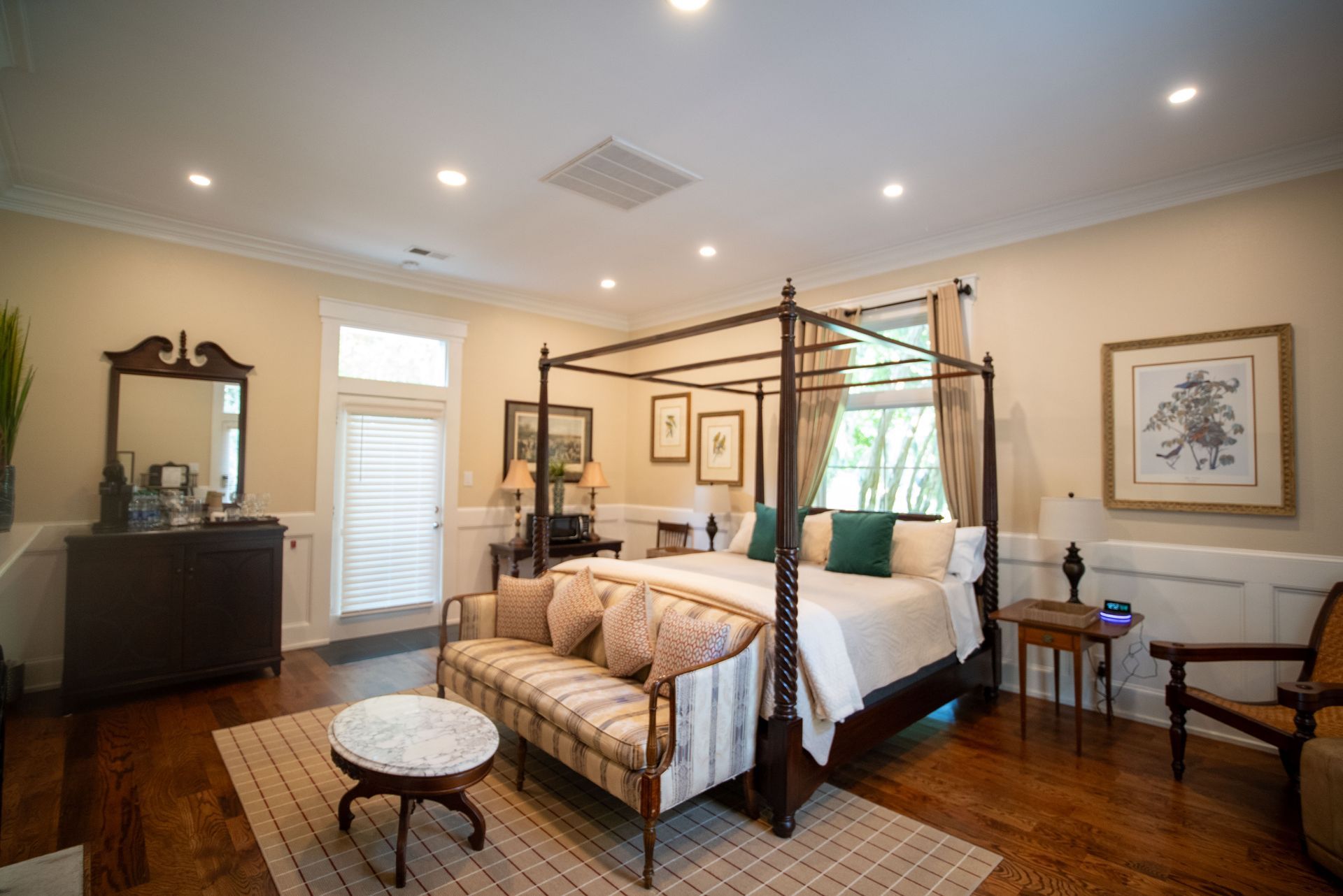 a bedroom with a canopy bed , couch , chair and mirror .